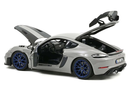 Silver sports car model with doors and hood open.