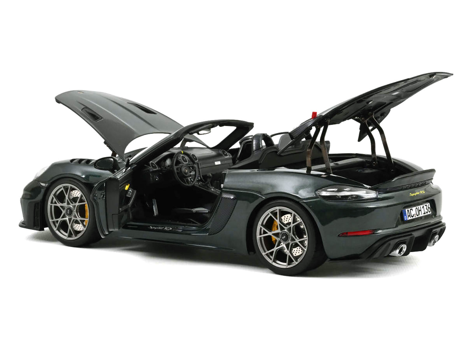 Dark green convertible car with open hood and trunk.